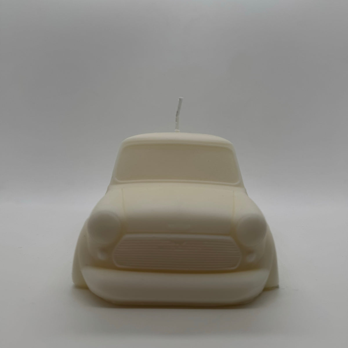 Vue de face de la bougie Austin Candle en cire de soja blanche, reproduisant la calandre et les phares d'une Mini Austin classique