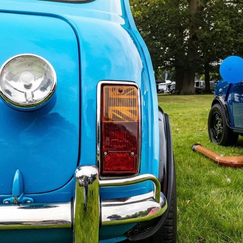 Feu arrière de Mini Austin bleu ciel avec kit adhésif Union Jack MK2-3 installé dans le cabochon, photographié sur une pelouse