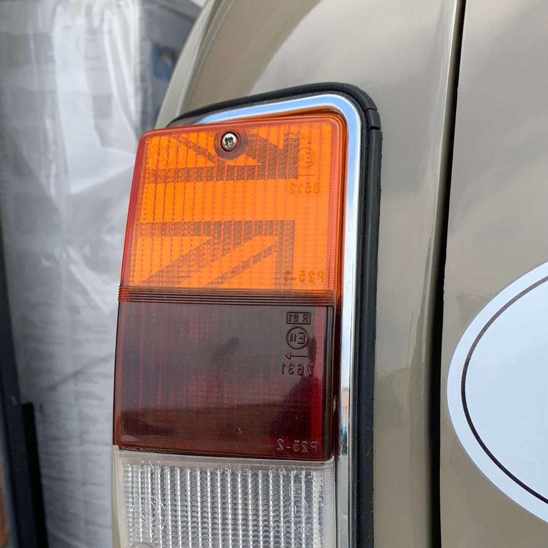 Gros plan du feu arrière d'une Mini Austin beige avec kit adhésif Union Jack MK4-7 installé à l'intérieur du cabochon orange