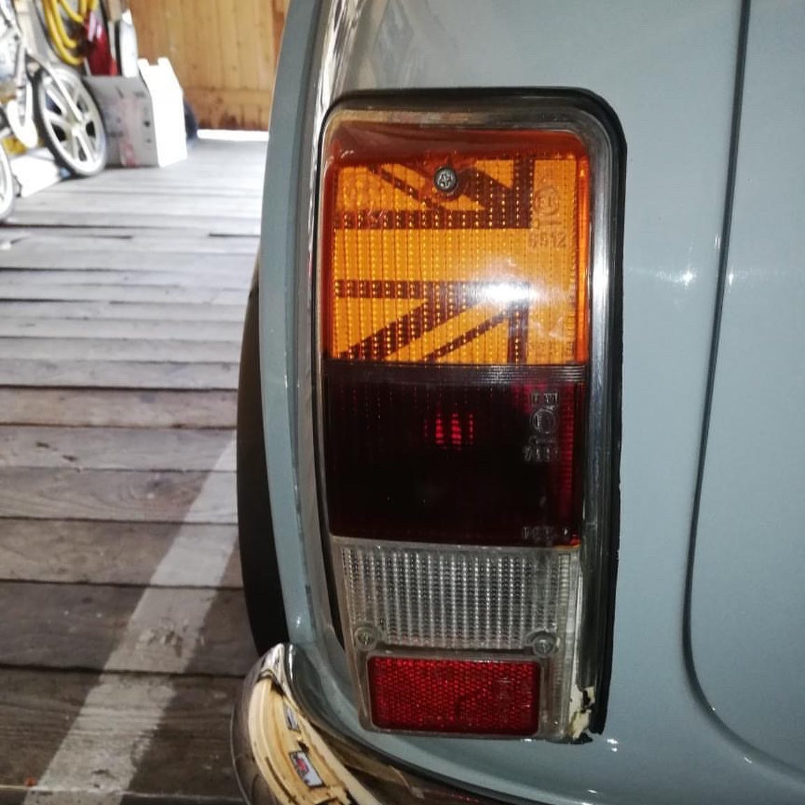 Kit adhésif Union Jack blanc installé à l'intérieur du cabochon orange d'un feu arrière de Mini Austin bleu-gris