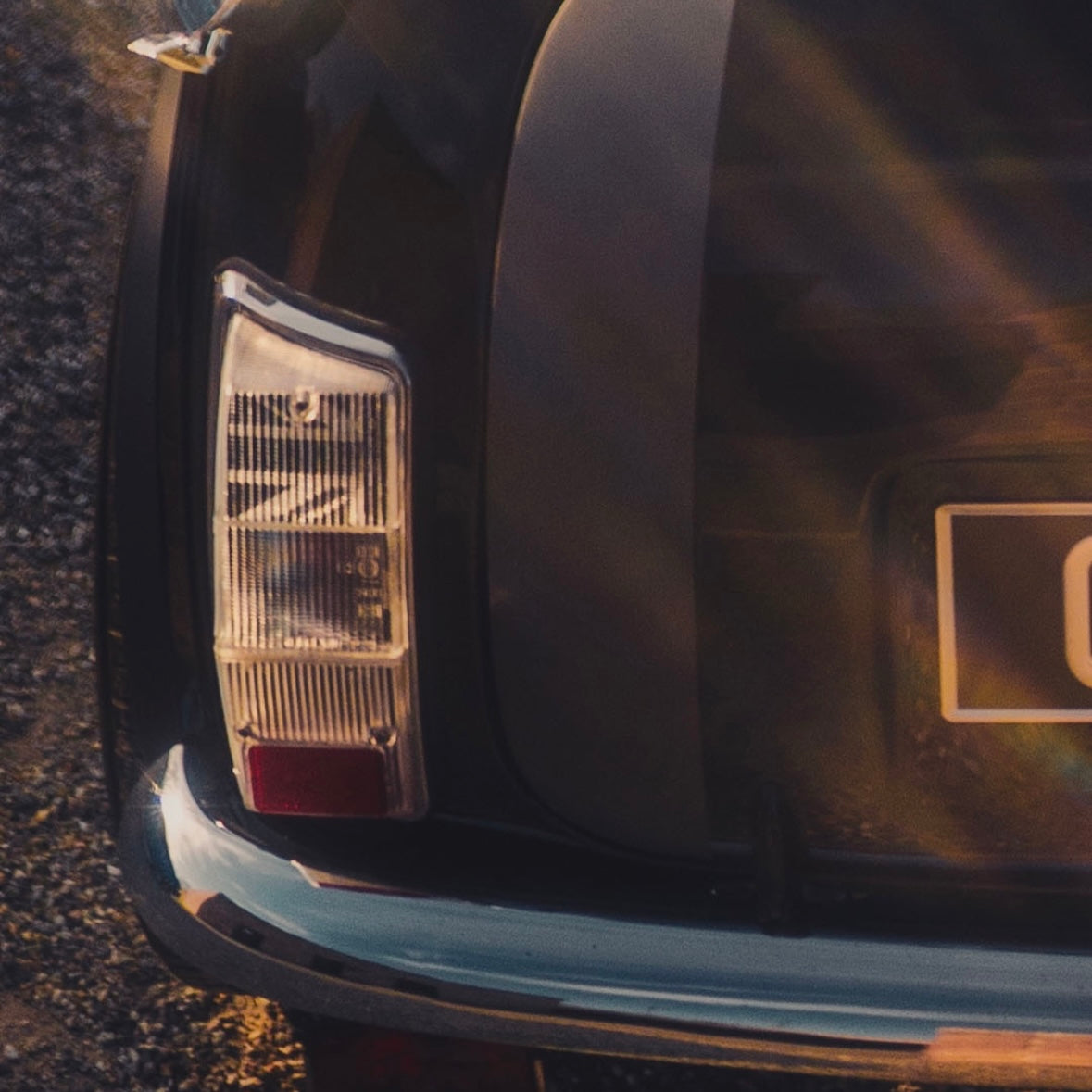 Feu arrière transparent de Mini Austin avec motif Union Jack noir installé à l'intérieur du cabochon, photographié au coucher du soleil